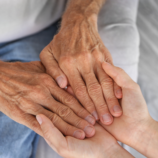 Hands of an
                  elderly person being held by both hands of a younger
                  person