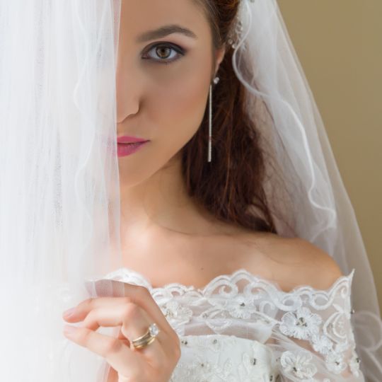 A
                              bride partially hidden behind a white
                              curtain